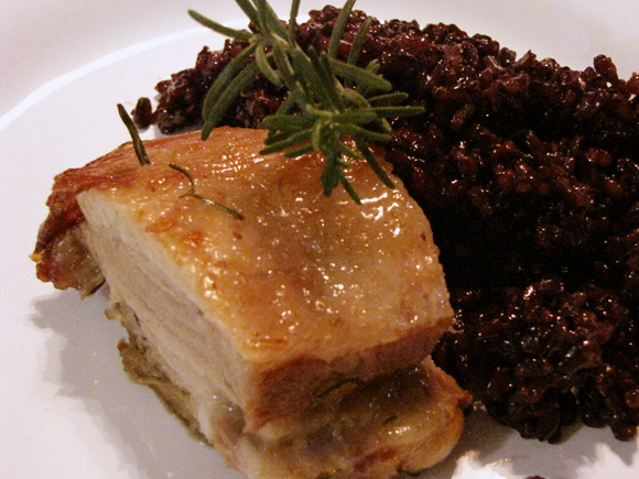 foto de um prato com um pedaço de uma costela suína assada arroz negro japonico e um ramo de alecrim para decorar